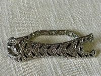 Full view of silver-tone articulating jaguar bracelet with rhinestones and black enamel detailing on a neutral fabric background.