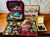 Wide view showing multiple jewelry boxes filled with assorted jewelry including necklaces, bracelets, earrings, rings