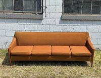 Front view of the four-seat mid-century modern couch showing burnt orange upholstery and teak wood elements on arms and legs.