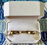 Photo of three vintage 10kt gold-filled rings in a white jewelry box on a patterned blue surface, showing two rings with tags