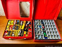 Overview of two open red carrying cases with compartments holding vintage diecast toy cars and micro-sized model airplanes separate by type.
