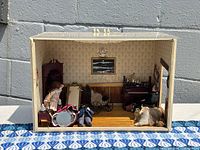 Front view of the dollhouse diorama showing entire room with furniture and figurines inside