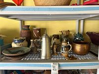 Overall shelf view showing steins, pottery pieces, coffee pot, utensils