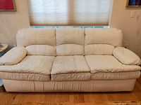 Front view of white leather couch showing three cushions and backrest