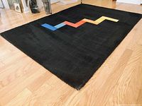 Full view of black wool rug with multicolor stepped line design