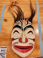 Front view of hand-painted Indonesian wood mask showing entire design and attached hair