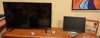 Insignia 40-inch TV and HP 17-inch monitor side by side on wooden surface