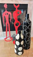 Front view of two red metal sculptures and two black polka-dot vases