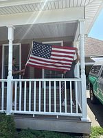 Individuals holding a United States flag on a porch