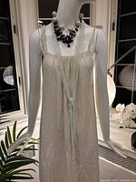 Full view of mannequin wearing white seed bead necklace and pearl/black necklaces