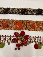 Three handmade belts side by side showing colour and embellishments