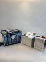 Overall view of paint-filled blue case and clear bin with canvases