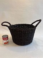 Front view of dark brown woven basket beside soup can for scale