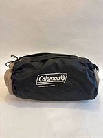Black nylon carry bag showing Coleman logo and compressed mattress within