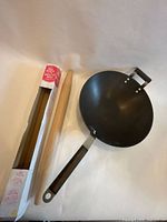 Rolling pin partially in box beside steel wok