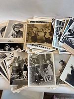 Multiple stacks of vintage 8x10 black-and-white Hollywood photos spread on table