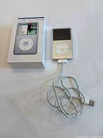 Front view showing iPod classic, USB cable and box