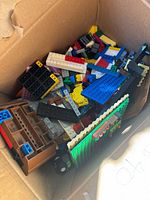 Open cardboard box filled with assorted LEGO pieces