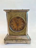 Front view of metal mantel clock showing dial with Ottoman numerals and engraved brass panel