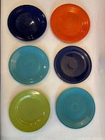 Six ceramic plates laid out: navy, orange, turquoise, navy, chartreuse green, turquoise
