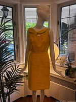 Full front view of yellow sheath dress on mannequin