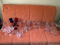 Full lot of assorted glassware on sofa