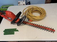 Hedge trimmer and coiled extension cord on table