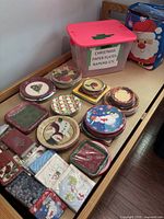 Overview of stacks of holiday plates and napkin packs on bench with labeled storage tote
