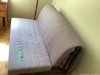 Futon in sofa position, showing quilted upholstery and curved metal side