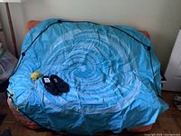 Full view of deflated blue inflatable float covering sofa, water shoes and yellow rope visible