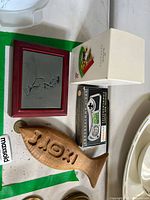 View of all items on table: Hallmark ornament box, wooden trinket box, metal cutter box, wooden fish
