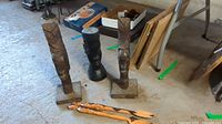 Photo showing three carved wooden figureheads standing on the ground with the carved wooden serving utensils laid in front.