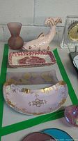 Photo shows pink ceramic fish figurine, pink frosted glass vase, a rectangular Mason's ironstone plate, two translucent glass plates with floral designs, and a crescent-shaped pink and gold glass dish.