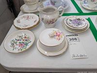 Mini china plates arranged together with small porcelain pitcher and covered dish, all with gold trim and floral patterns