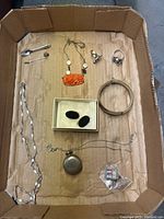 Complete overview of all jewelry items in cardboard box on brown paper background.