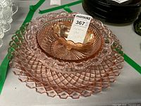 Stacked pink Depression glass platter and bowls with amber Carnival glass bowl on top, showing overall lot composition