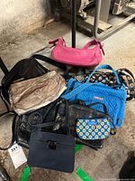 Overview of 7 handbags showing different styles, colors and materials including a blue Vera Bradley quilted handbag, pink, black, gold and patterned bags.