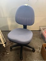 Full view of a blue office chair showing molded seat and backrest with visible stains on the backrest.