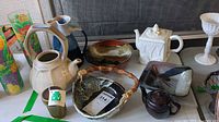 Overview of lot with pitcher, bowls, egg coddler, various teapots including Lenox, displayed on a table.