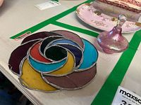 Photo showing the multicolor stained glass decorative plate with swirl pattern and visible crack.