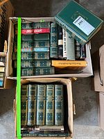 Top view of two boxes of vintage books, showing multiple volumes and titles including a Thackeray series set with decorative spines.