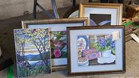 Three framed prints stacked leaning against each other showing detailed floral art and stained glass designs.