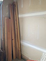 Stack of various length wood boards leaning against wall