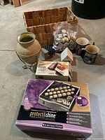 Overview of lot showing basket, vase, boxed hair rollers, boxed travel iron, mugs, tealights, house décor