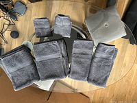 All six folded blue-grey towels on glass table