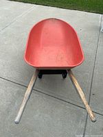 Top view of red metal wheelbarrow showing interior tray and wood handles