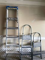 Aluminum ladder with blue cap, two grey folding step stools