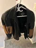 Jez black leather jacket with tan sleeve panels on hanger