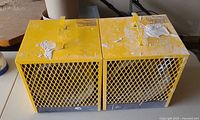 Top view showing twin yellow caged heater units with handles and paint splatter
