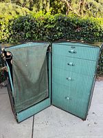 Opened wardrobe steamer trunk showing four drawers, hanging compartment with green fabric lining.